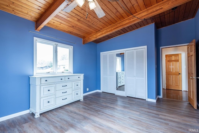 unfurnished bedroom featuring lofted ceiling with beams, wood finished floors, a ceiling fan, wood ceiling, and baseboards