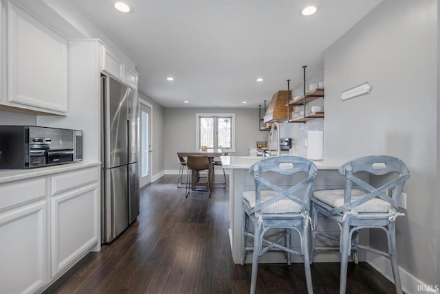 kitchen featuring dark wood-style flooring, high end fridge, recessed lighting, light countertops, and white cabinetry