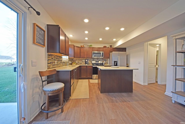 kitchen featuring decorative backsplash, stainless steel appliances, light countertops, light wood-style floors, and a sink