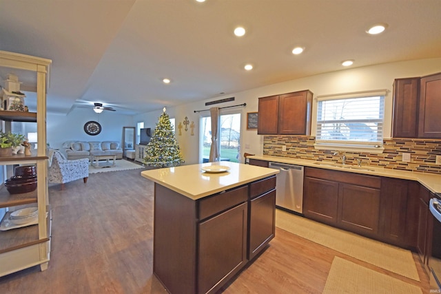 kitchen featuring a center island, decorative backsplash, light wood-style floors, a sink, and dishwasher