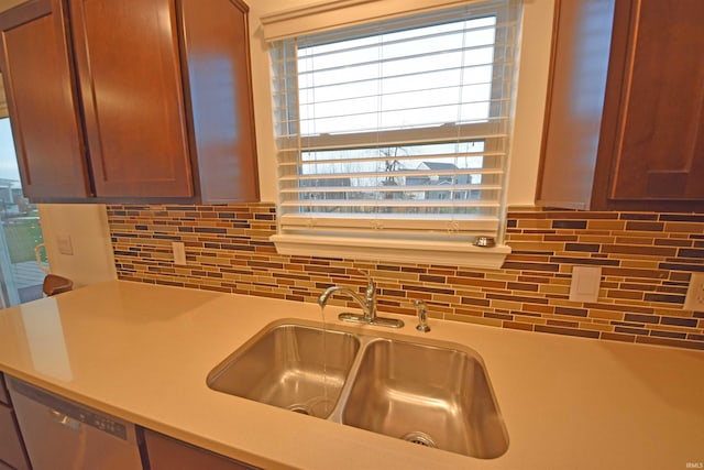 kitchen with dishwasher, light countertops, backsplash, and a sink