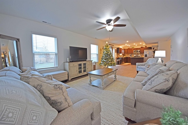 living area with light wood finished floors, ceiling fan, and visible vents