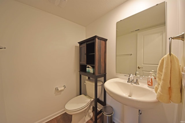 bathroom with toilet, baseboards, visible vents, and a sink