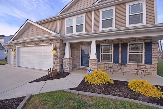 view of front of home featuring covered porch, stone siding, driveway, and a garage