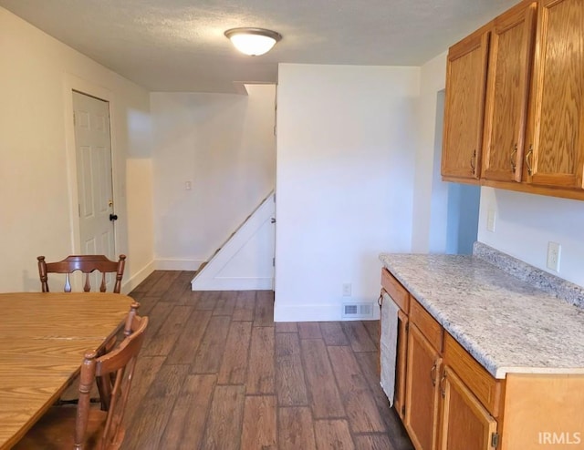 unfurnished dining area featuring baseboards, visible vents, dark wood finished floors, and a textured ceiling