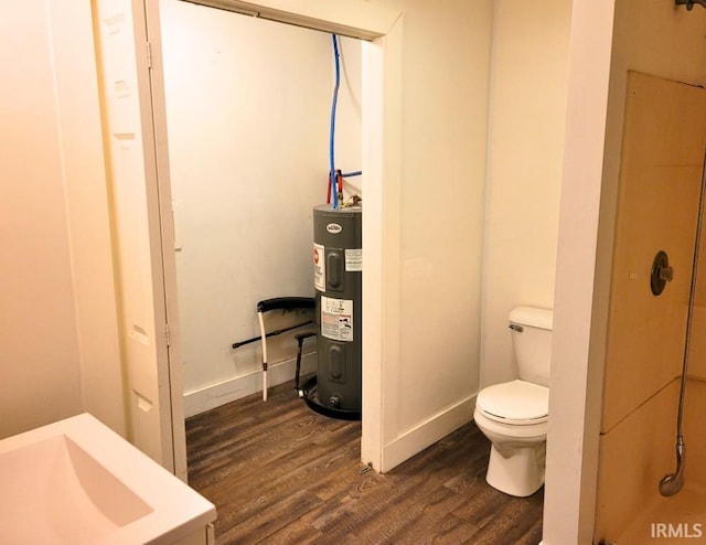 bathroom featuring toilet, a sink, wood finished floors, baseboards, and water heater