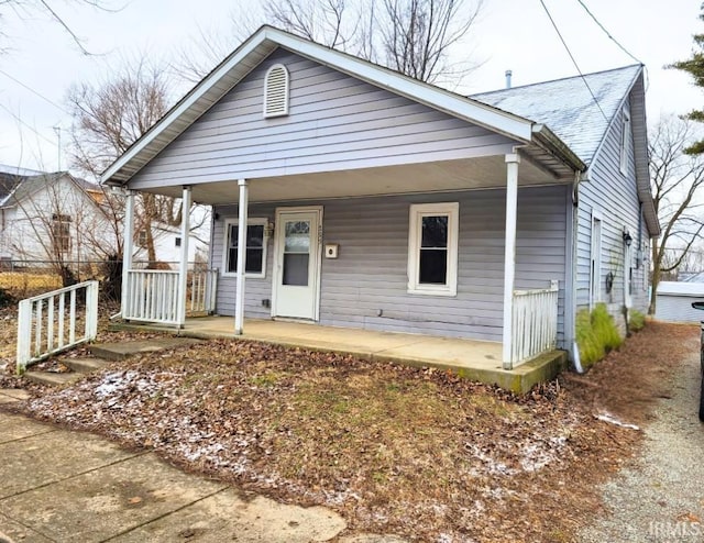 bungalow-style home featuring a porch and roof with shingles