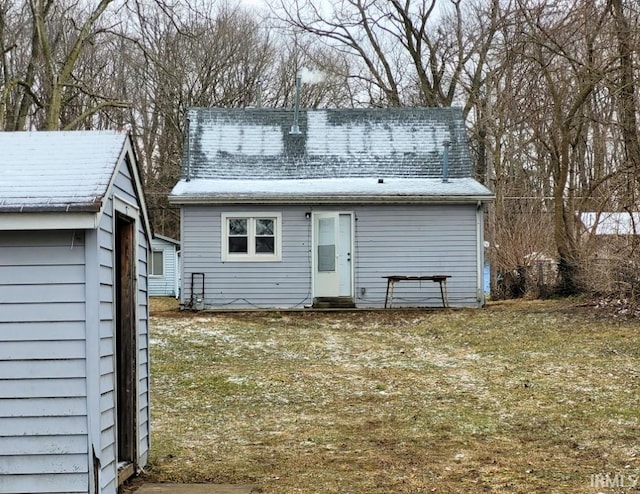 back of house with entry steps, a shingled roof, and an outdoor structure