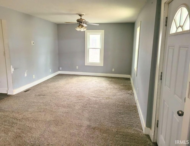 interior space with dark colored carpet, a healthy amount of sunlight, visible vents, and baseboards