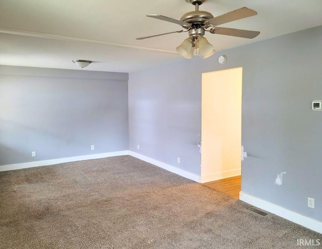 carpeted empty room featuring baseboards, visible vents, and a ceiling fan