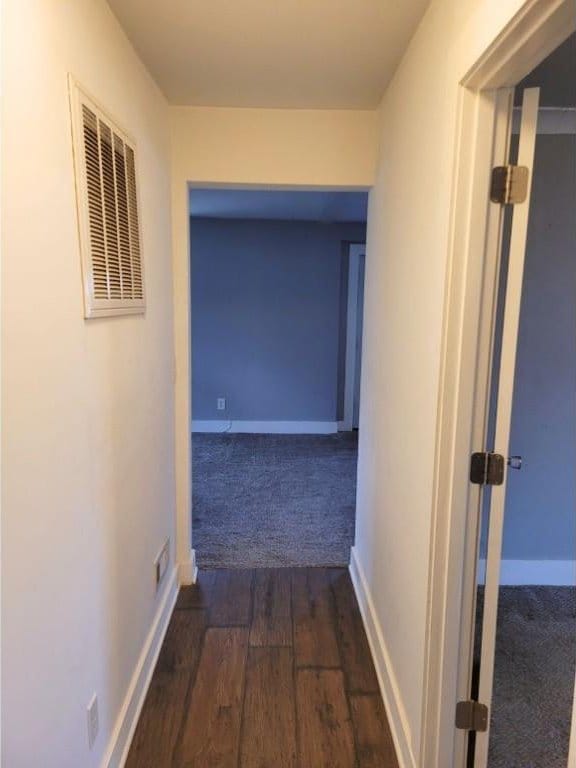 corridor featuring dark wood finished floors, visible vents, and baseboards