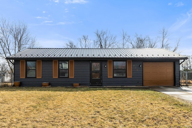 ranch-style home featuring metal roof, driveway, an attached garage, and a front yard