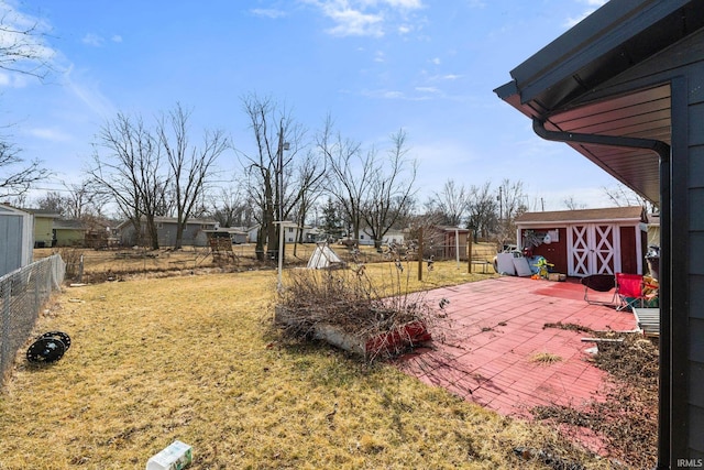 view of yard with fence, a storage unit, an outbuilding, and a patio