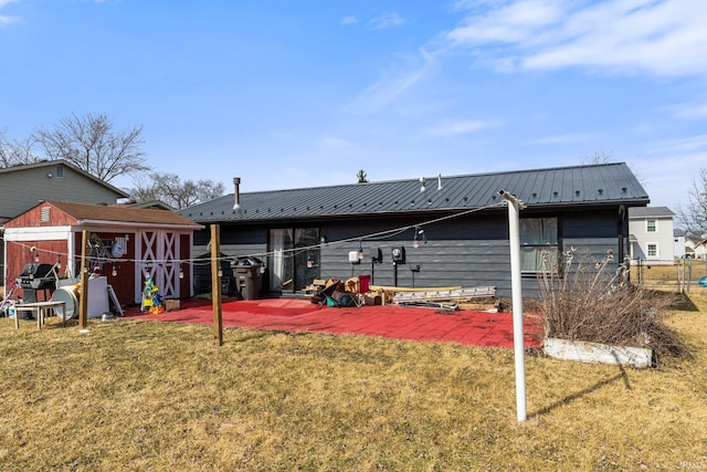 rear view of property featuring metal roof, a patio, an outdoor structure, a yard, and a storage unit