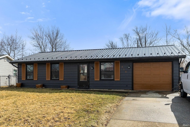 view of front of property featuring a garage, a front yard, metal roof, and driveway