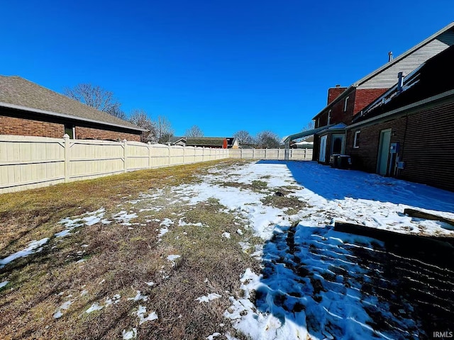 yard covered in snow with a fenced backyard