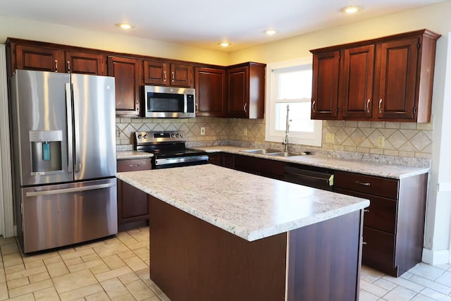 kitchen featuring light countertops, appliances with stainless steel finishes, a kitchen island, and a sink