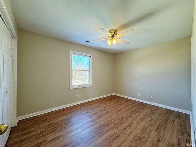 unfurnished bedroom featuring visible vents, baseboards, a ceiling fan, wood finished floors, and a closet