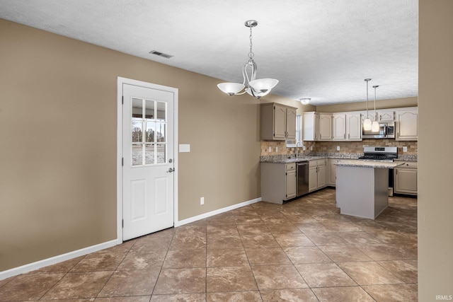 kitchen with stainless steel appliances, tasteful backsplash, visible vents, a kitchen island, and baseboards