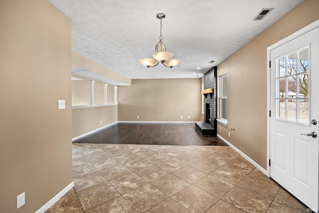 tiled foyer with a textured ceiling, a fireplace, visible vents, and baseboards