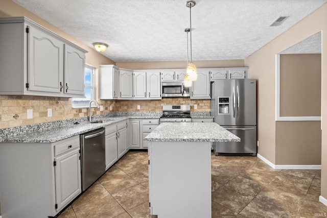 kitchen featuring stainless steel appliances, visible vents, decorative backsplash, a sink, and a kitchen island