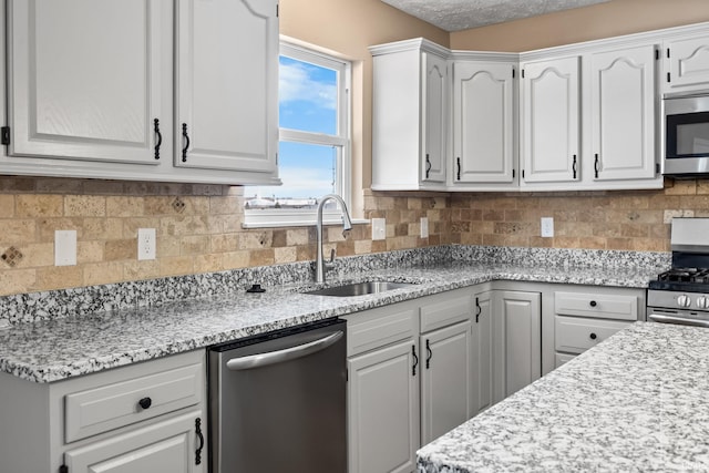 kitchen featuring stainless steel appliances, tasteful backsplash, a sink, and white cabinetry