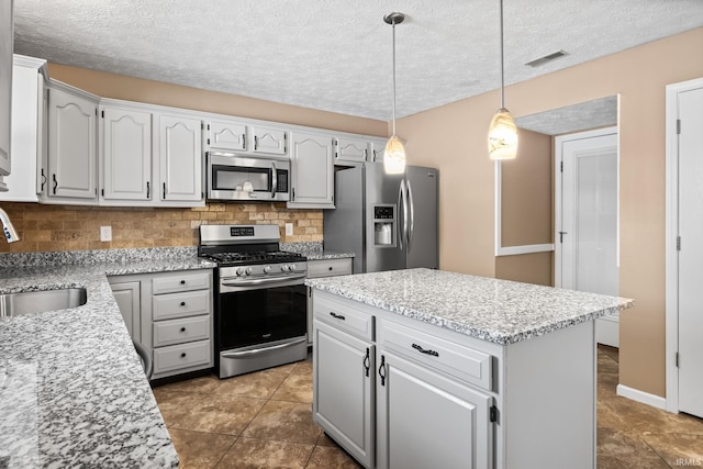 kitchen with visible vents, appliances with stainless steel finishes, a sink, pendant lighting, and backsplash