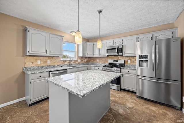 kitchen featuring decorative light fixtures, stainless steel appliances, tasteful backsplash, a kitchen island, and a sink