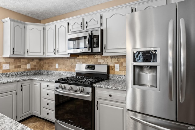 kitchen featuring stainless steel appliances, tasteful backsplash, white cabinets, a textured ceiling, and light stone countertops