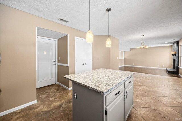 kitchen with a center island, a fireplace, visible vents, open floor plan, and a textured ceiling