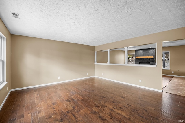 spare room featuring hardwood / wood-style flooring, baseboards, visible vents, and a textured ceiling