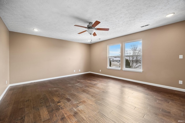 spare room featuring dark wood-style flooring, visible vents, and baseboards