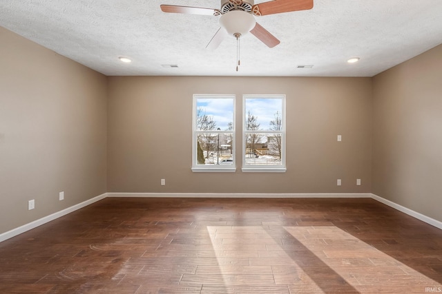 spare room featuring a textured ceiling, dark wood-style flooring, visible vents, and baseboards