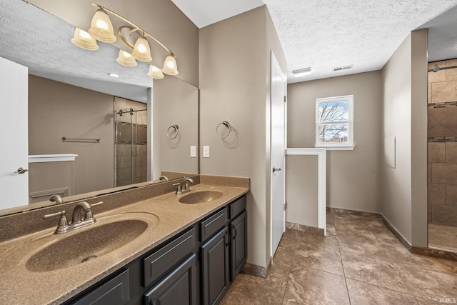 bathroom with visible vents, a sink, and tiled shower