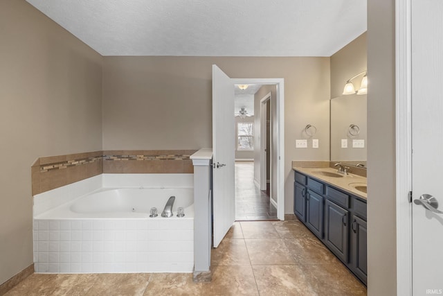 bathroom with a textured ceiling, a garden tub, a sink, tile patterned floors, and double vanity