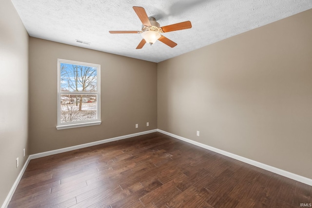 spare room with baseboards, visible vents, dark wood finished floors, and a textured ceiling