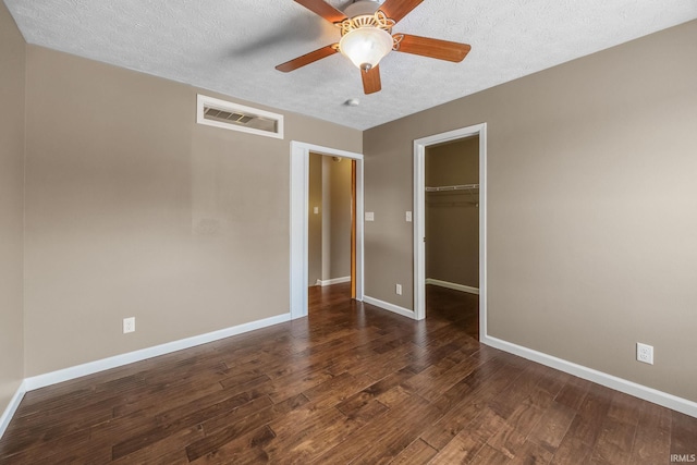 unfurnished bedroom featuring a textured ceiling, visible vents, baseboards, a closet, and dark wood finished floors