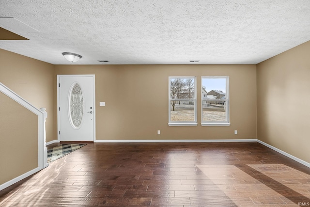 entryway featuring dark wood-type flooring, visible vents, a textured ceiling, and baseboards