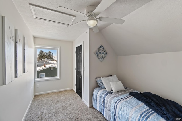 carpeted bedroom featuring attic access, baseboards, a ceiling fan, lofted ceiling, and a textured ceiling