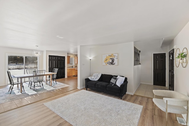 living area with visible vents, an inviting chandelier, light wood-style flooring, and baseboards