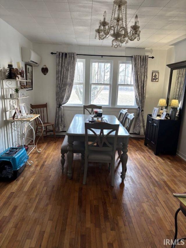 dining room featuring hardwood / wood-style flooring, an AC wall unit, and an inviting chandelier