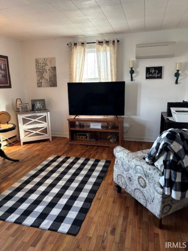 living room with wood finished floors, baseboards, and a wall mounted AC