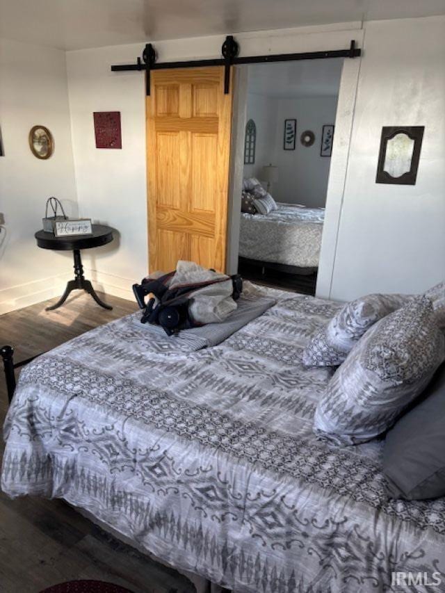 bedroom with a barn door and wood finished floors