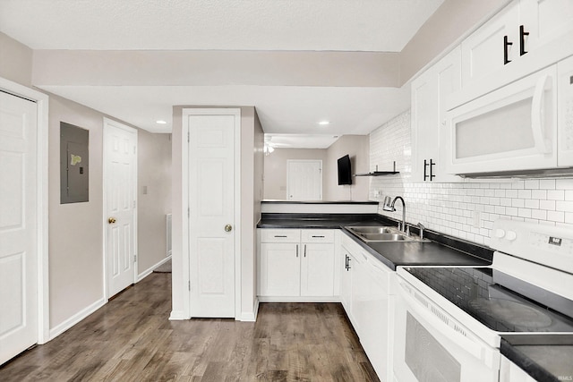 kitchen with dark countertops, white appliances, electric panel, and a sink