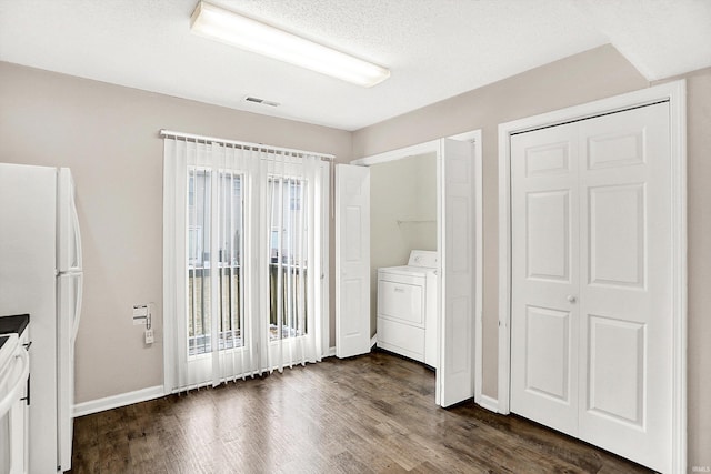 interior space with washer / dryer, freestanding refrigerator, multiple windows, and dark wood finished floors