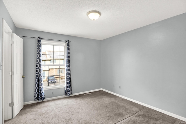 carpeted empty room featuring a textured ceiling, visible vents, and baseboards