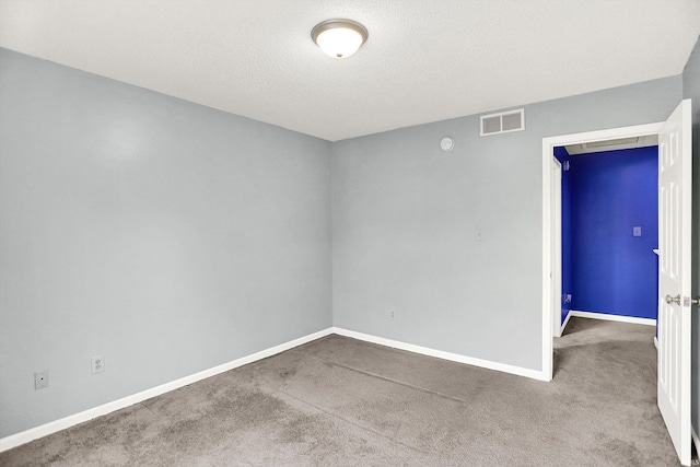 spare room with a textured ceiling, carpet floors, visible vents, and baseboards