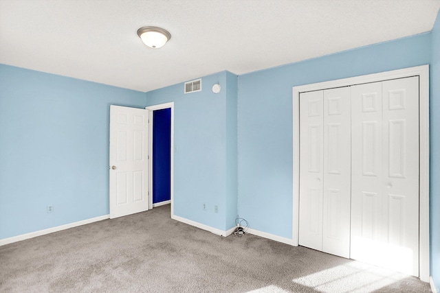 unfurnished bedroom featuring carpet, a closet, visible vents, and baseboards