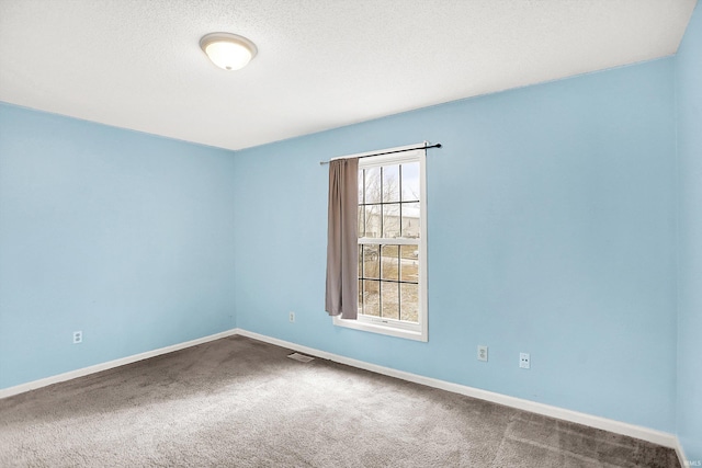 spare room featuring visible vents, a textured ceiling, baseboards, and carpet flooring