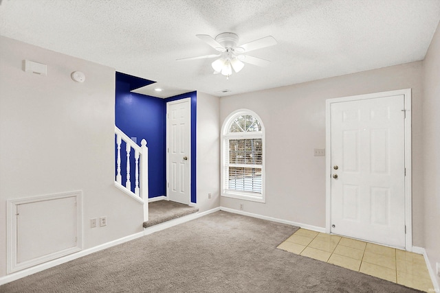 foyer entrance featuring a textured ceiling, stairway, carpet flooring, and baseboards